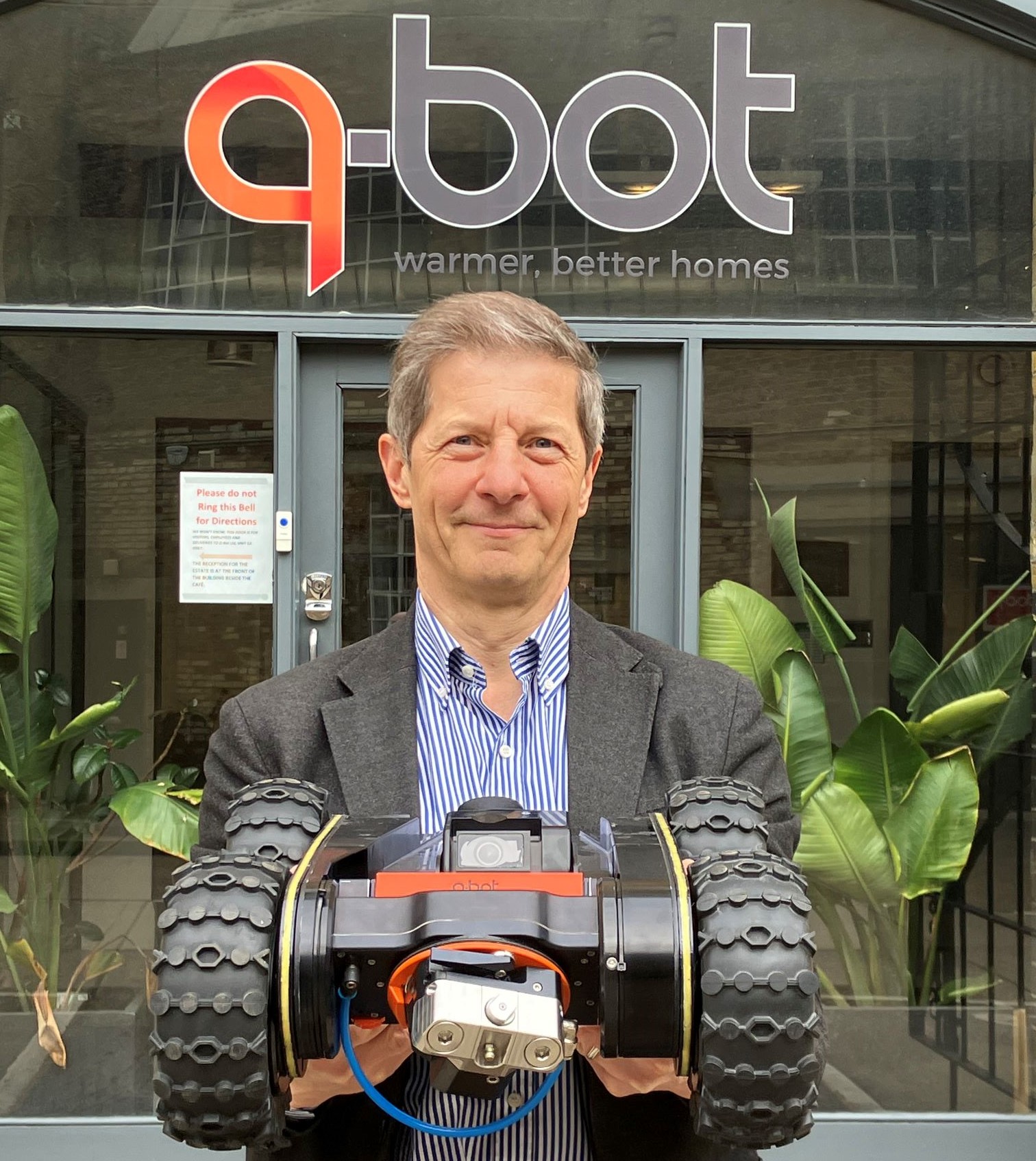 Man holding robot outside Q-Bot Head Office
